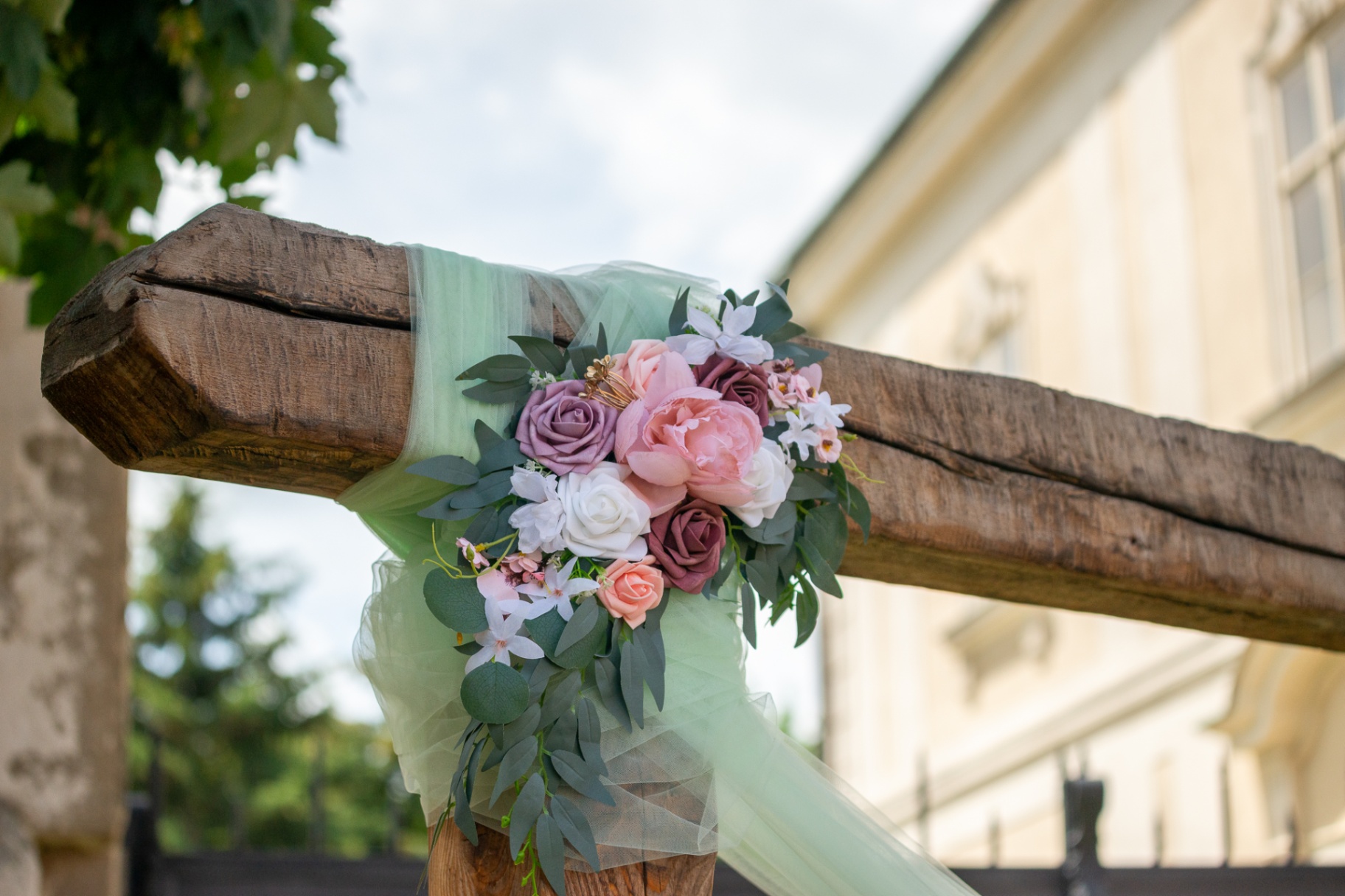 Detail květinové výzdoby s růžemi a tylem na dřevěném obřadním oblouku